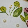Hand embroidered floral arrangement with pearls on white fabric detailed green leaves