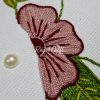 Detailed hand embroidery of large pink and red stitched flower on clean white fabric background