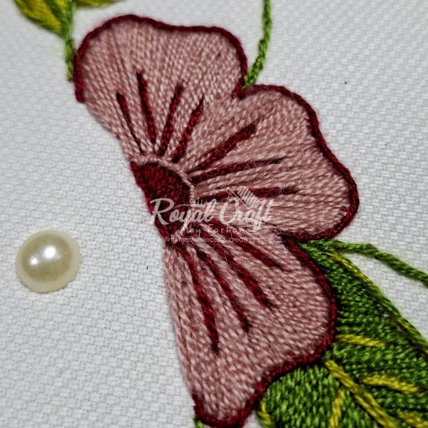 Detailed hand embroidery of large pink and red stitched flower on clean white fabric background