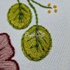 Close-up of beautiful hand embroidered vibrant green leaves on white cotton textile surface texture