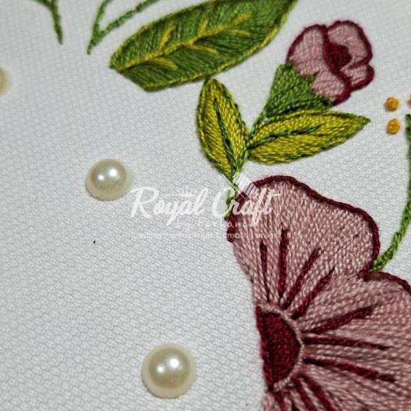 Macro shot of elegant floral embroidery featuring pink petals green leaves and applied pearl beads